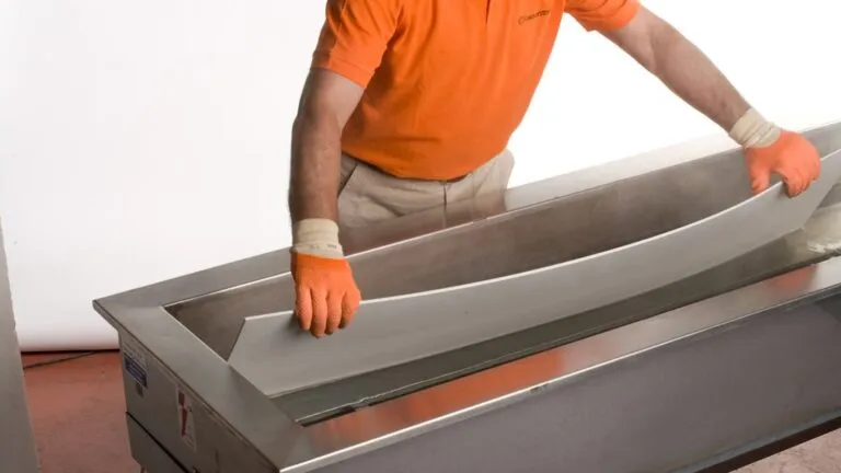 עובד מרים רצועת אבן קיסר מתוך אמבט חימום כחלק מתהליך כיפוף בחום.