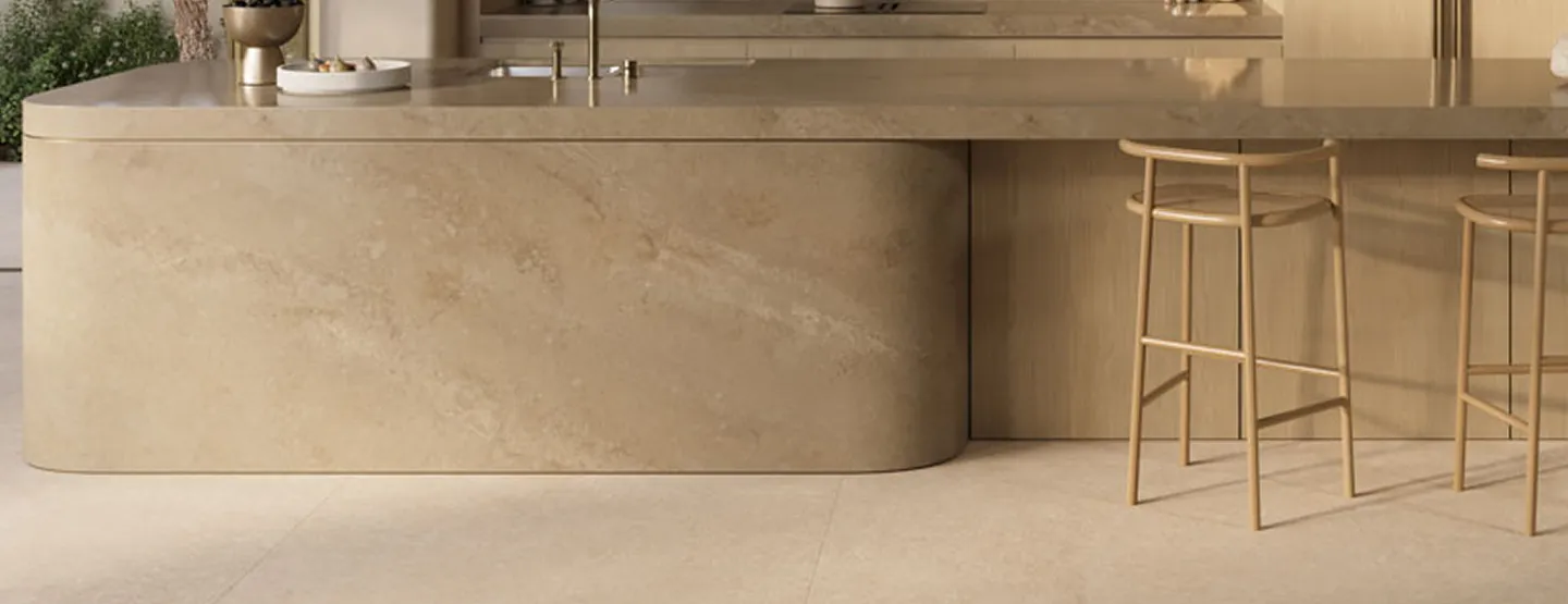 אי מטבח מעוצב עם חזית ופלטת אבן קיסר בגוון בהיר וקווים מעוגלים.